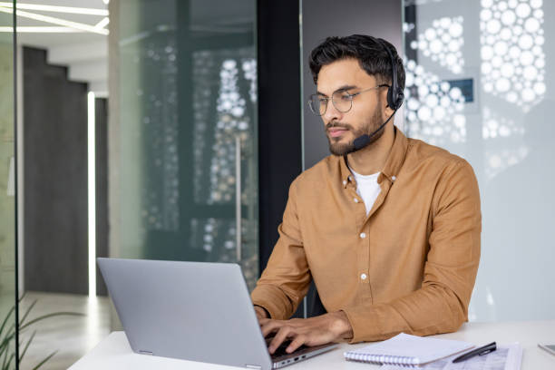 istock Focused customer service representative working on laptop with headset in modern office 2156268377