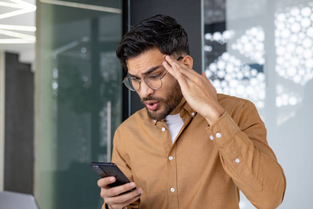 istock Shocked young man receives surprising news on smartphone in modern office setting 2156268551