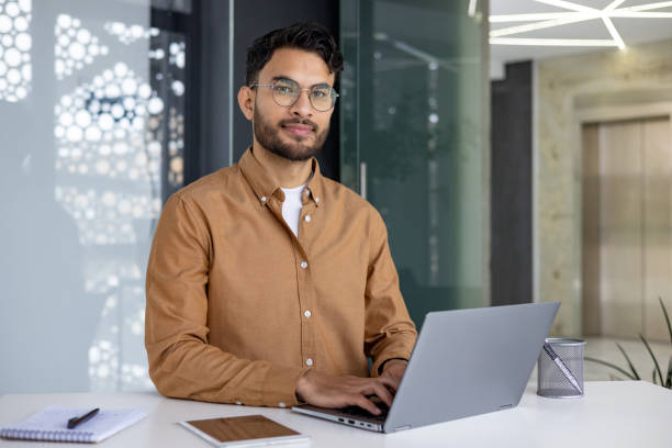 istock Confident young man working on laptop in modern office setting 2156270212