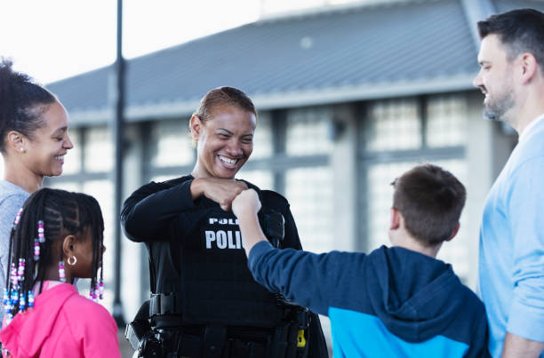 istock Policewoman talking to group, fist bump with boy 2156271784