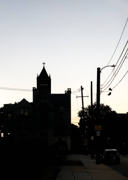 Outlining of a church steeple during sunset time in wilimington, Delaware off of Tatnall Street surrounded by cable wires and shoes hung up on wires.