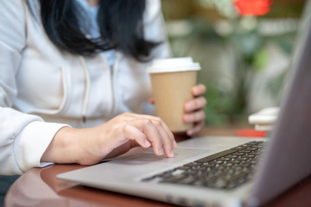 istock A woman is typing on her laptop computer, sipping coffee, working remotely at a cafe. 2156274431