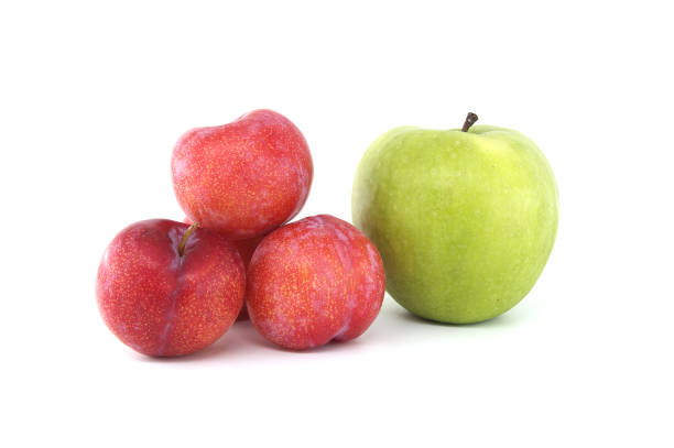 Assortment of fresh fruits set against a white backdrop, including vivid green apples and crimson plums