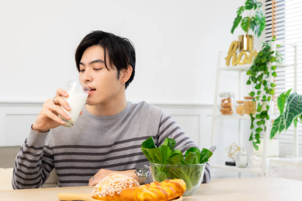 istock Asian man  drinking milk and eating vegetable  breakfast  in kitchen at home . 2156279886