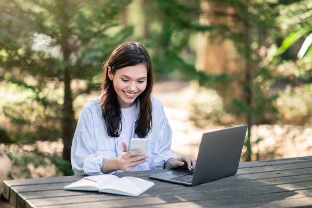 istock Contented young woman multitasking with a smartphone and laptop 2156284361