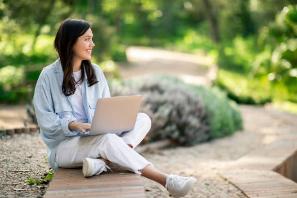 istock Woman using laptop outdoors at public park 2156284489