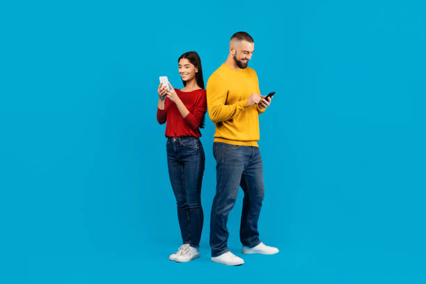istock Young Man and Woman Using Smartphones Against Blue Background 2156285436