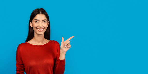 istock Smiling Woman in Red Top Showing Blank Space 2156285537
