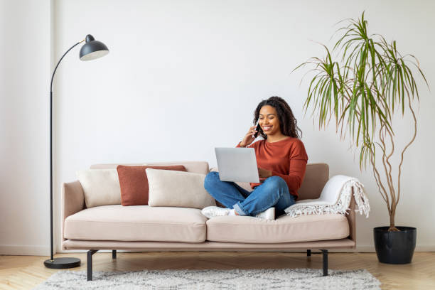 istock Online Work. Young Black Woman Working With Laptop And Cellphone At Home 2156287521