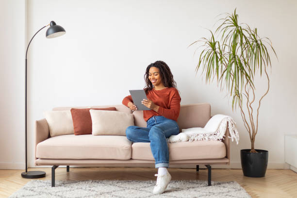 istock Beautiful young black woman using digital tablet at home 2156287567