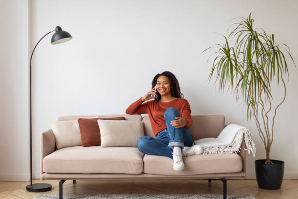 istock Relaxed young black woman enjoying conversation on her mobile phone at home 2156287603