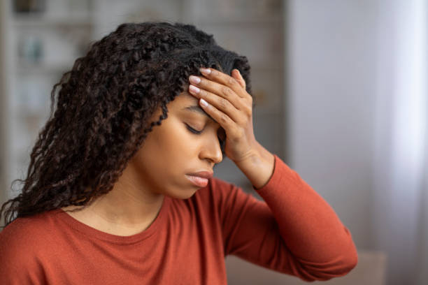istock Sick young black woman suffering from headache at home, touching her forehead 2156287705