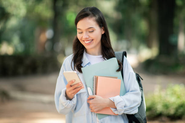 istock Engaged young female student with a cheerful expression, using a smartphone 2156287829