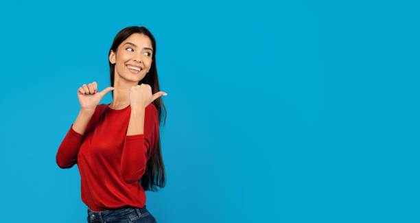 Great Offer. Smiling Young Woman Pointing At Copy Space Behind Her Back