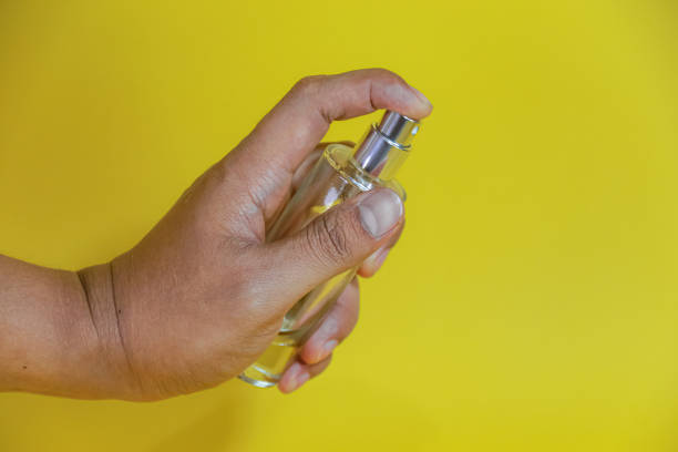 istock hand holding perfume bottle on yellow background 2156289833
