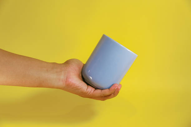 istock hand holding a blue ceramic mug on a yellow background 2156289864