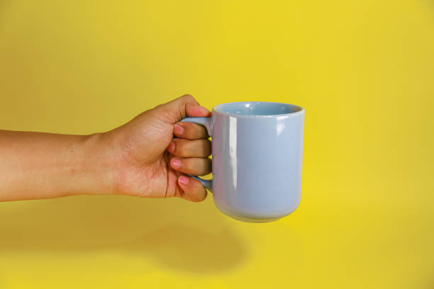 istock hand holding a blue ceramic mug on a yellow background 2156289873