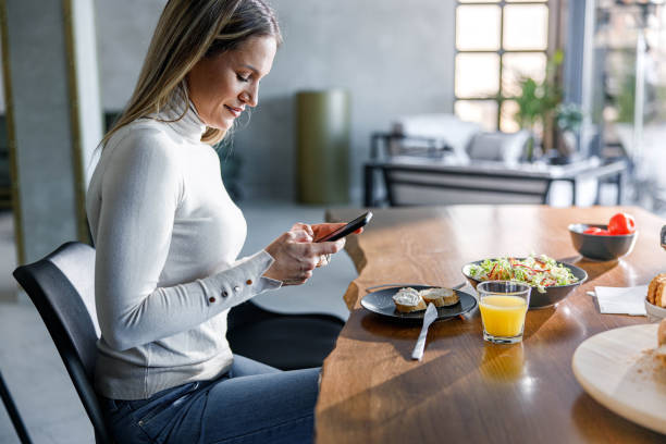 istock Happy woman using cell phone during her meal at home. 2156293278