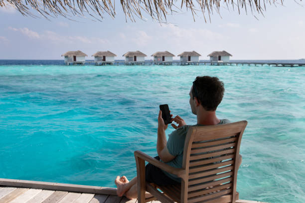 istock mobile internet, online banking, man using smartphone on the beach in Maldives 2156296554