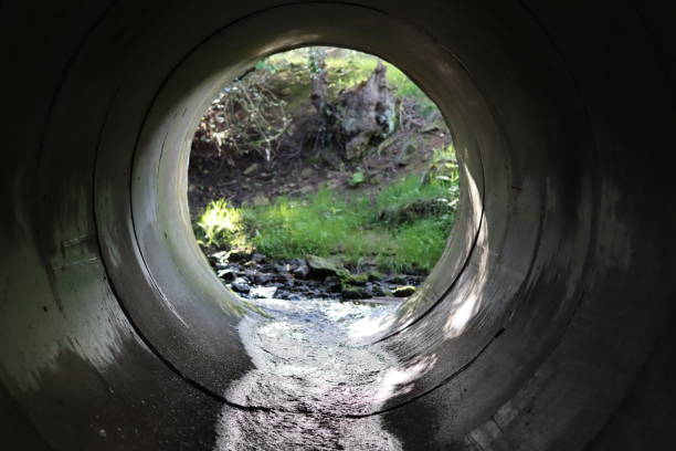 istock View through a round concrete tunnel carrying a stream beneath a road 2156298472