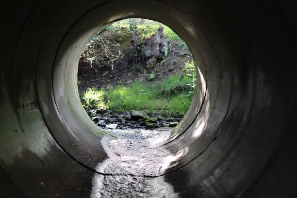 istock View through a round concrete tunnel carrying a stream beneath a road 2156298574