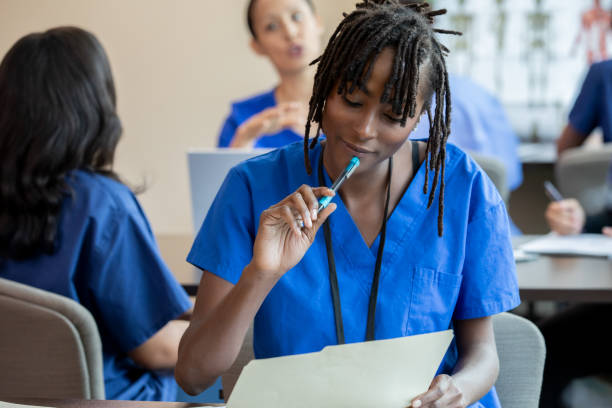 istock Engaged in the lecture, a nursing student wearing blue scrubs concentrates on taking detailed notes. 2156299849