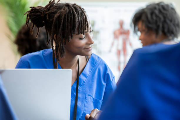 istock Among classmates, a nursing student in scrubs simultaneously engages in the discussion and documents lecture points on her laptop. 2156299852