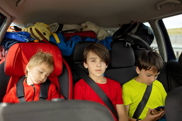 istock Three boys in car seats, traveling in car, sleeping and playing on mobile, while travel 2156302057