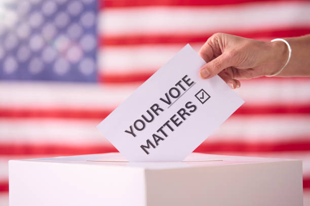 istock Hand Placing Ballot in Box With American Flag 2156303777