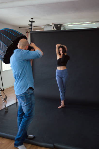 istock Photographer shooting a model in a studio with a softbox 2156303875