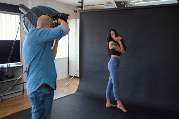 istock Photographer shooting a model in a studio with a softbox 2156304087