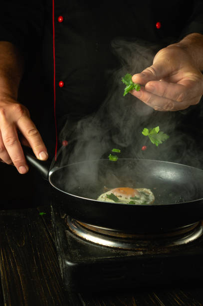 istock Adding aromatic parsley to a hot pan with eggs. A chef prepares an egg lunch in a restaurant kitchen 2156305159