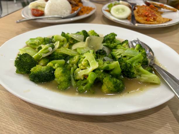 istock Delicious stir-fried broccoli with onions in a savory sauce, served on a white plate 2156308217