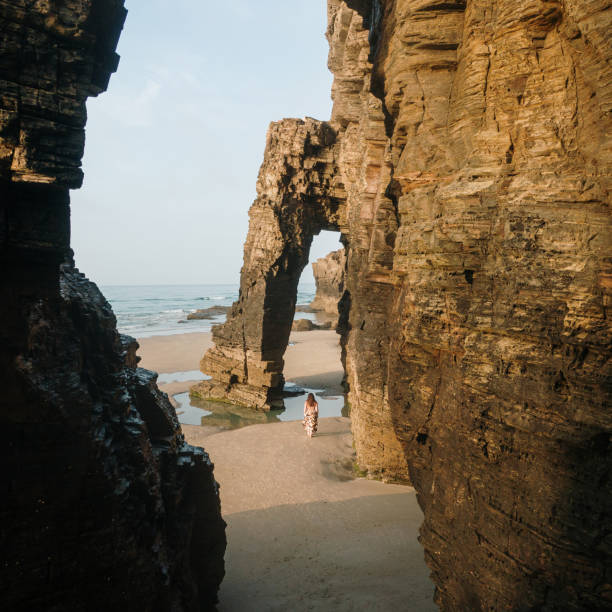 Woman walking on a beach with natural rock arches