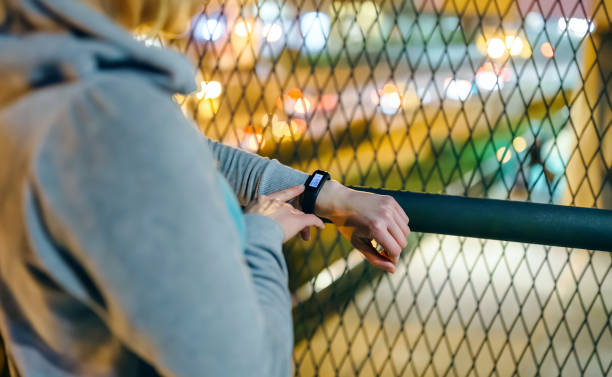istock Unrecognizable female hands touching digital wrist band to check step counter after walking at night 2156320343