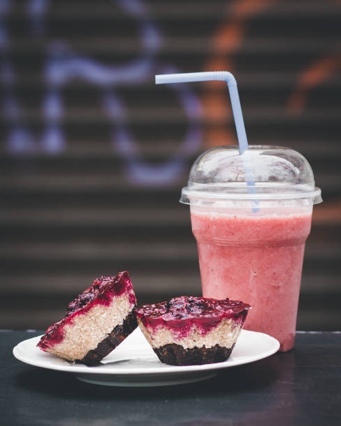 Strawberry smoothie and two peaces of a  cheesecake on a white plate