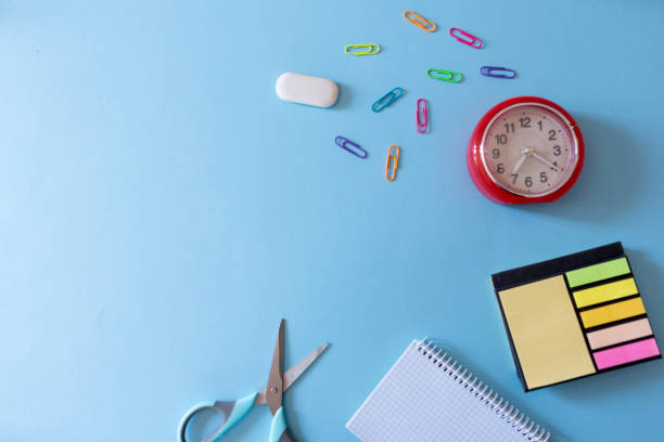 istock School or office supplies with clock on blue background. 2156323144