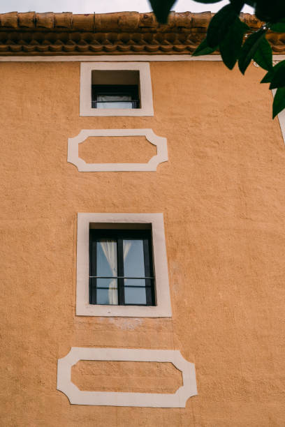 istock Geometric Windows on Ochre Mediterranean-Style Facade Under Clear Sky. The harmony of traditional architecture and the simplicity of design in a Mediterranean setting 2156324006