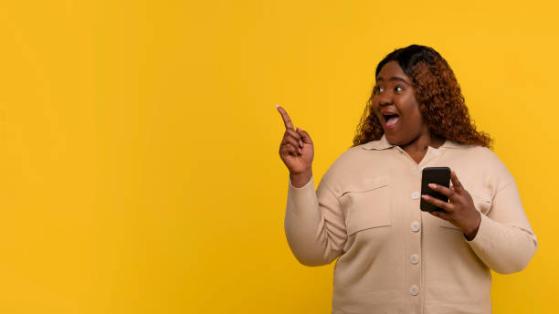 istock Amazed chubby black woman with cell phone, blank space 2156324234