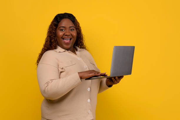 istock Cheerful overweight black lady holding laptop computer 2156324238