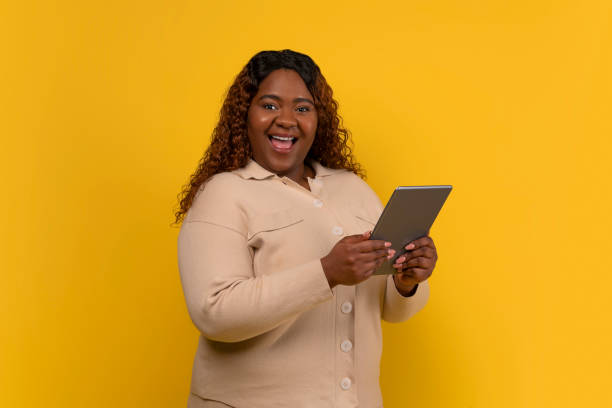 istock Happy chubby african american lady holding digital tablet 2156324267