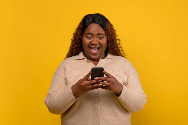 istock Overjoyed plump african american lady reading message on smartphone 2156324279