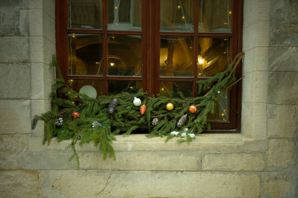 istock A wooden window is decorated with Christmas balls and Christmas tree branches. 2156325384