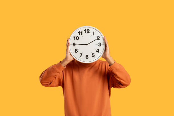 Man holding clock in front of face