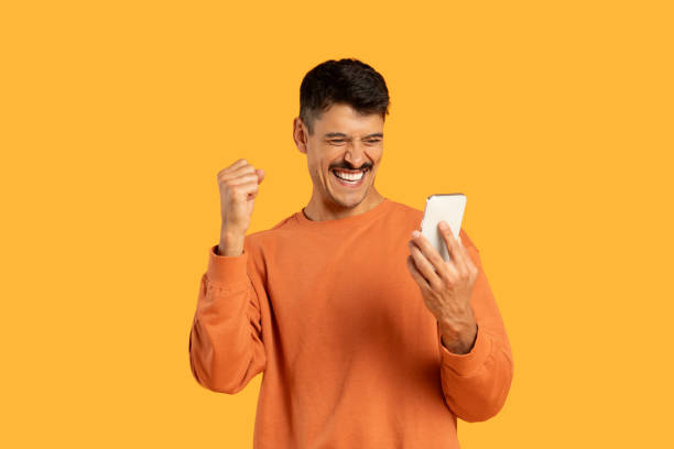 Happy man celebrating with smartphone in hand
