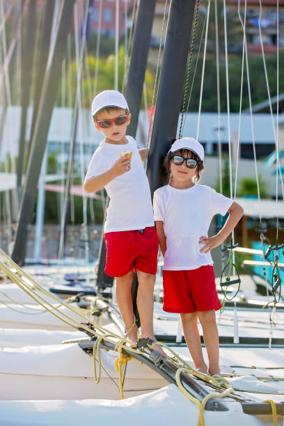 Two beautiful children, boy brothers, standing on a boat, smiling, summertime on sunset