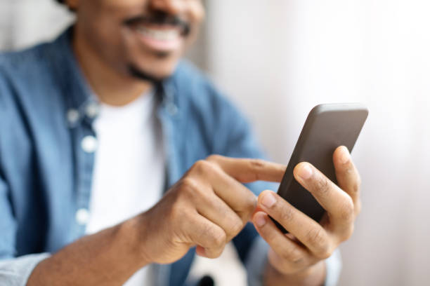 istock Smiling Black Man Using Smartphone Indoors During Daytime 2156332291
