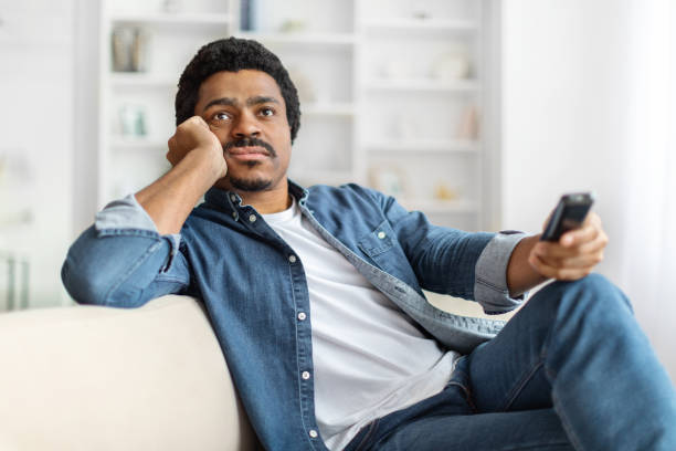 istock Relaxed Black Man Lounging On Sofa With Remote Control 2156332371