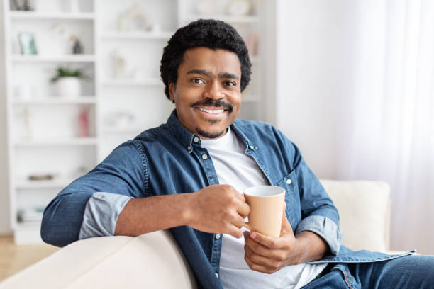 istock Smiling man holding a coffee mug comfortably 2156332402