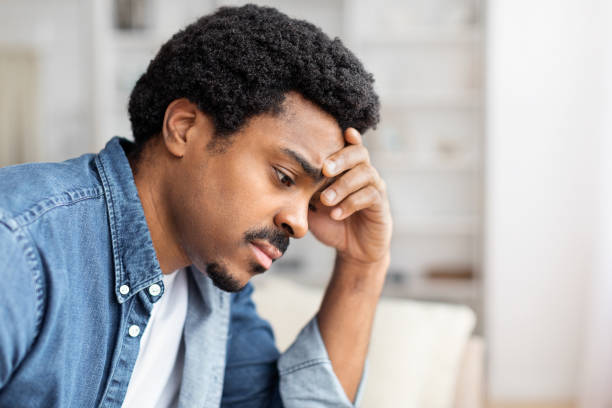 African American hiding face with hands at home